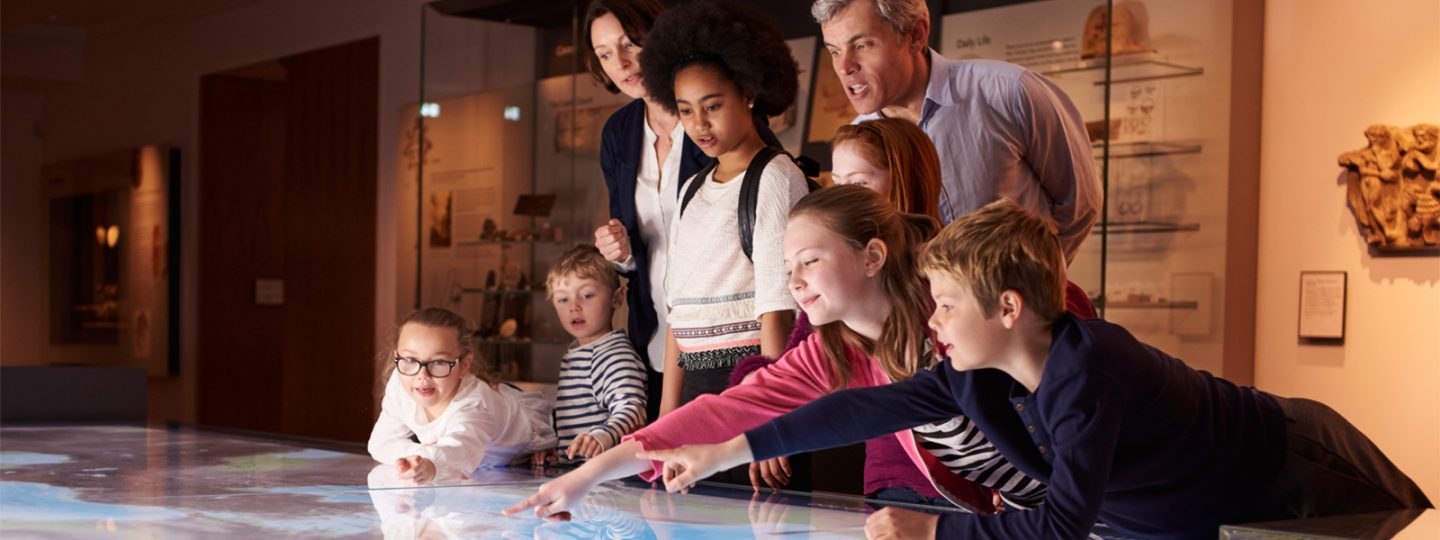 A group of teachers and students look over a map on a table.